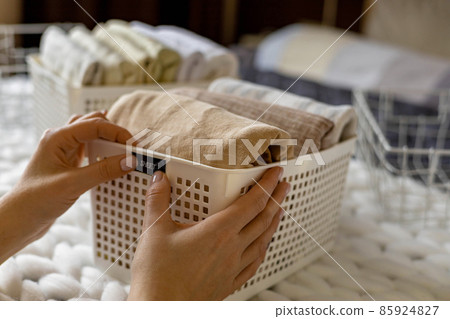Woman hands neatly folded linens and towels use Marie Kondo method with sticky label tags Woman hands neatly folded linens and towels use Marie Kondo method with sticky label tags 85924827