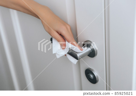 Cleaning door handles with an antiseptic wet wipe and gloves. Sanitize surfaces prevention in hospital and public spaces against corona virus. Woman hand using towel for cleaning home room door link. Cleaning door handles with an antiseptic wet wipe and gloves. Sanitize surfaces prevention in hospital and public spaces against corona virus. Woman hand using towel for cleaning home room door link. 85925021