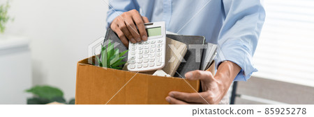 Resignation Concept The man in light blue shirt standing at the desk and putting the calculator and other stuff into the box 85925278