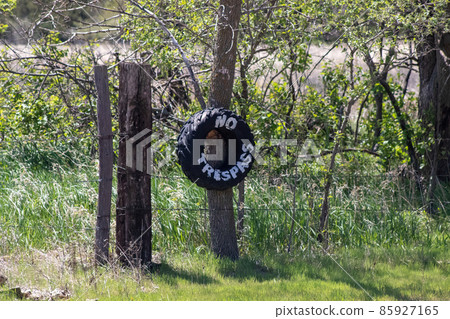 No Trespassing tire sign on barb wire fence  85927165