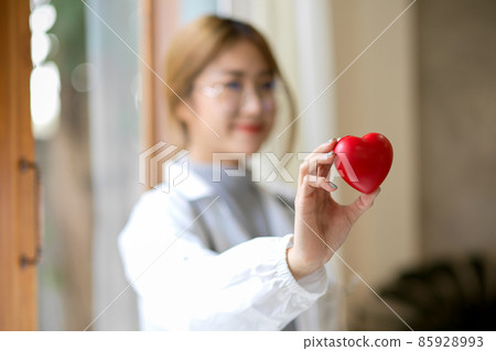 A female doctor in white coat holding a heart model. A female doctor in white coat holding a heart model. 85928993