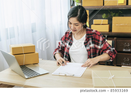 Online seller Close up hands Young asian woman typing laptop keyboard checking online order, check goods stock delivery package shipping postal. Asian woman startup small business at home office 85933169