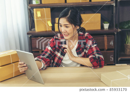 Asian woman startup small business at home office. Online seller entrepreneur young asian woman use tablet checking online order. Woman using tablet check stock goods supply delivery package shipping 85933170