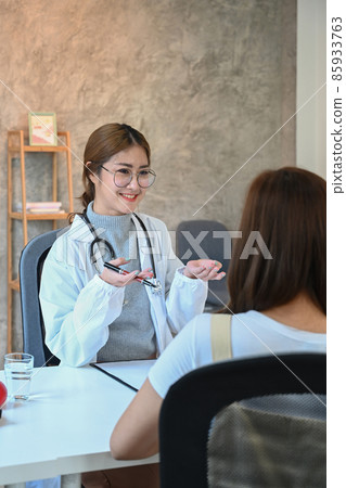 Beautiful female doctor in white medical uniform giving advice to her female patient. 85933763