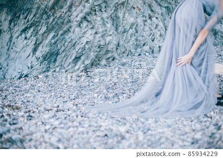 The focus of beautiful stones, rocks on the seashore, disfocus girl in a dress with the edge of the picture 85934229
