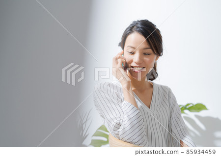 30 多歲的女性,在室內打電話 30 多歲的女性,在室內打電話 85934459