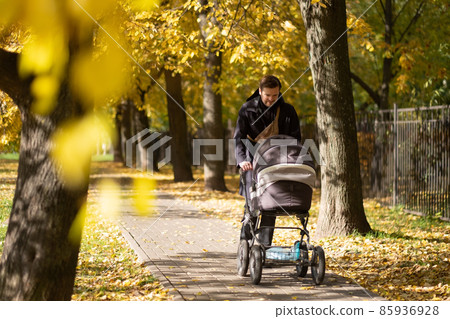 Happy young father with pram during the walk in nature Happy young father with pram during the walk in nature 85936928