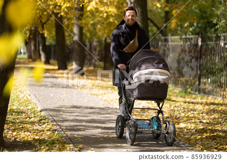 Happy young father with pram during the walk in nature Happy young father with pram during the walk in nature 85936929