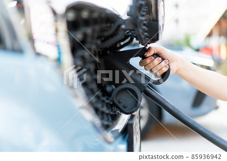Woman preparing to charge her EV car at EV Charging station. 85936942
