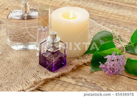 Bottles of perfume, candle and lilac flowers on wooden background. 85936978