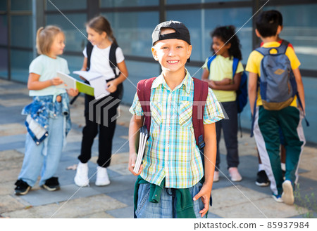 Smiling primary school boy standing outdoors 85937984