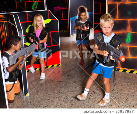 Preteen girls and boys with laser pistols playing laser tag 85937987