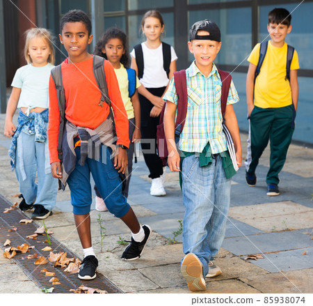 Smiling tweenagers walking outside school building on autumn day Smiling tweenagers walking outside school building on autumn day 85938074