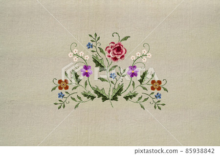 Bouquet of twigs with small white flowers, violets, poppies, twigs with blue flowers and a red-pink rose in the middle on a beige fabric background. 85938842