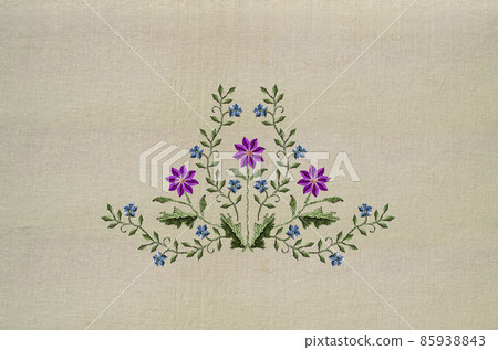 Embroidery of a bouquet with purple clementine flowers and delicate violets on a beige fabric background. 85938843