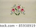 Embroidery of a delicate bouquet with sprigs of red-pink roses and delicate violets on a beige fabric background 85938919