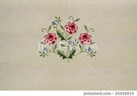 Embroidery of a delicate bouquet with sprigs of red-pink roses and delicate violets on a beige fabric background Embroidery of a delicate bouquet with sprigs of red-pink roses and delicate violets on a beige fabric background 85938919