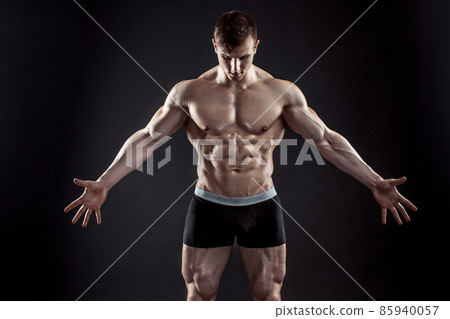 Muscular bodybuilder guy doing posing over black background Muscular bodybuilder guy doing posing over black background 85940057