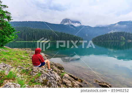 Young boy enjoying view of black lake or Crno jezero in Durmitor nature park, Montenegro 85940252