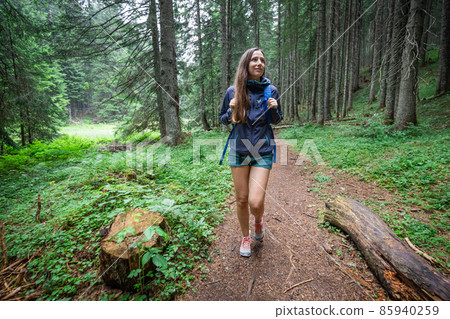 Young smiling woman with backpack walking on footpath in the forest 85940259