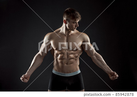 Muscular bodybuilder guy doing posing over black background 85942878