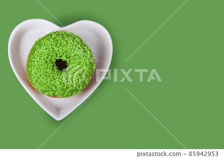Green donut in a plate in a shape of a heart 85942953