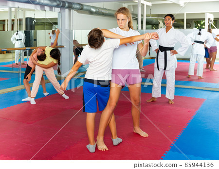 Kids in pair exercising self-defense movements Kids in pair exercising self-defense movements 85944136