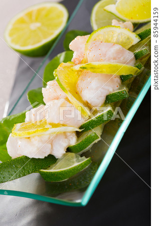 Ceviche from alaska pollock on a glass plate with lime and herbs 85944159
