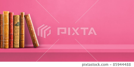 Row of old books on pink shelf. Background banner Row of old books on pink shelf. Background banner 85944488