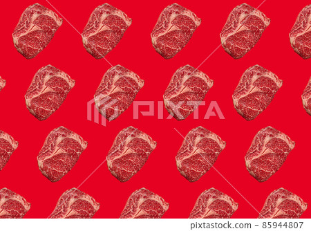 Pattern made of raw meat beef marbled prime cut steak Ribeye on red clean background Pattern made of raw meat beef marbled prime cut steak Ribeye on red clean background 85944807