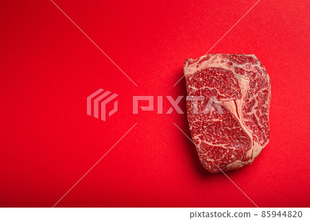 Raw meat beef prime cut steak Ribeye on clean red background from above, beefsteak concept banner minimalism Raw meat beef prime cut steak Ribeye on clean red background from above, beefsteak concept banner minimalism 85944820