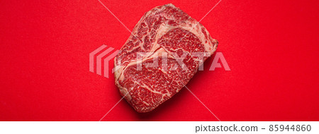 Raw meat beef prime cut steak Ribeye on clean red background from above, beefsteak concept banner minimalism Raw meat beef prime cut steak Ribeye on clean red background from above, beefsteak concept banner minimalism 85944860