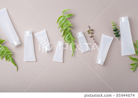 Skincare organic beauty product bottles, green plant leaves on gray background Skincare organic beauty product bottles, green plant leaves on gray background 85944874