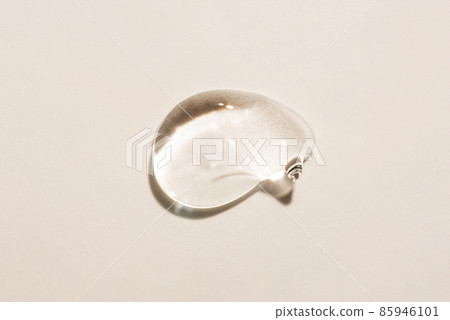 Transparent hyaluronic acid gel drop on a beige background. 85946101