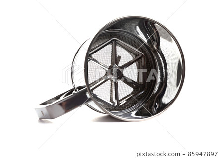 a sieve for flour in the form of a metal cup with a handle lies on its side on a white isolated 85947897