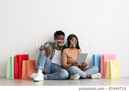 Beautiful black lovers using digital tablet, shopping online Beautiful black lovers using digital tablet, shopping online 85949718