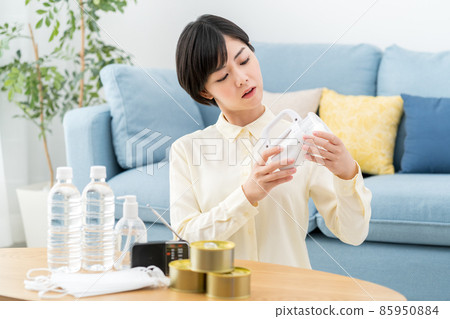 一位婦女在家裡檢查防災用品、疏散用品和應急食品的庫存 85950884