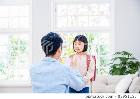 Father wearing a mask on his elementary school daughter 85951153