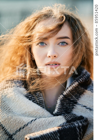 Close-up portrait of pretty young woman with long wavy hair in sunlight outdoors 85951420