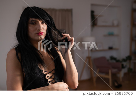 Homosexual preening in front of the mirror. A transgender man combing a wig. Homosexual preening in front of the mirror. A transgender man combing a wig. 85955700
