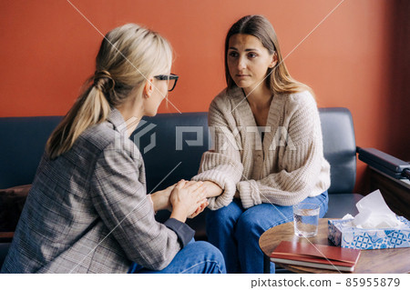 Woman psychotherapist holding the hand of a woman client supports and comforts. 85955879