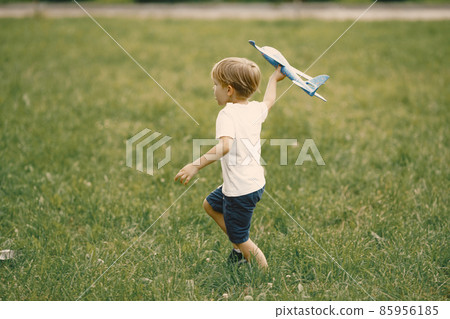 Little boy playing with airplane toy on a grass Little boy playing with airplane toy on a grass 85956185