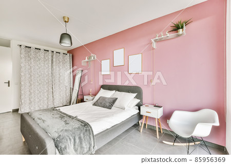 Stunning bedroom with a pink wall and paintings on it and an unusual chandelier 85956369