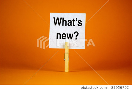 White paper with text 'Whats New', clip on wood clothespin. Beautiful orange background. Business concept. Copy space. White paper with text 'Whats New', clip on wood clothespin. Beautiful orange background. Business concept. Copy space. 85956792