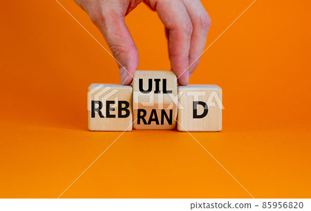 Rebrand and rebuild symbol. Businessman turnsa the wooden cube and changes the word rebrand to rebuild. Beautiful orange table, orange background. Business rebrand and rebuild concept. Copy space. Rebrand and rebuild symbol. Businessman turnsa the wooden cube and changes the word rebrand to rebuild. Beautiful orange table, orange background. Business rebrand and rebuild concept. Copy space. 85956820