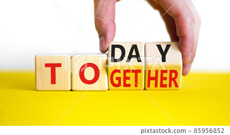 Today we are together symbol. Businessman turns wooden cubes and changes the word together to today. Beautiful yellow table, white background, copy space. Business and today we are together concept. Today we are together symbol. Businessman turns wooden cubes and changes the word together to today. Beautiful yellow table, white background, copy space. Business and today we are together concept. 85956852