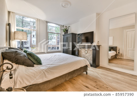 Luxurious bedroom with a large soft bed covered with a fluffy gray blanket 85957390