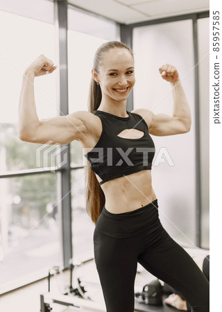 Fit woman with pony tail shows arm muscles, - Stock Photo [85957585] -  PIXTA