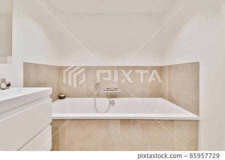 Beautiful bathroom with a big bathtub and white walls Beautiful bathroom with a big bathtub and white walls 85957729