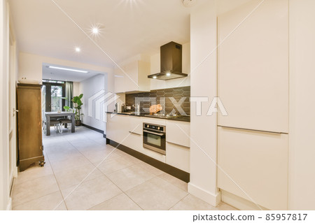 Interior of contemporary kitchen with stylish black cupboards and appliances near dining area in contemporary apartment 85957817